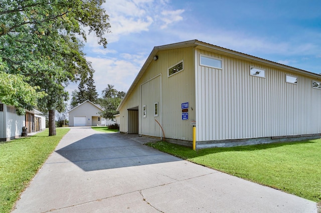 view of home's exterior featuring a detached garage, an outbuilding, and a lawn