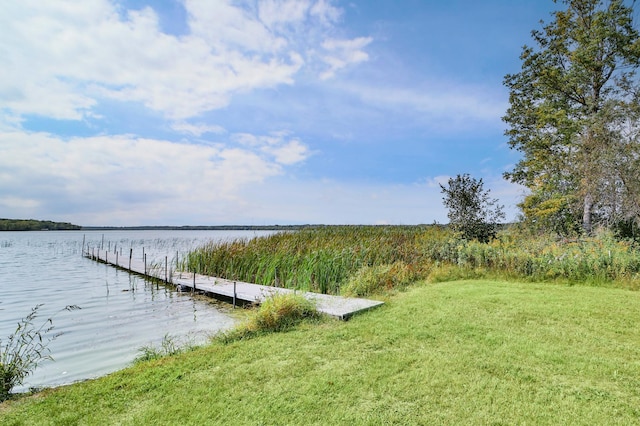 view of dock with a yard and a water view