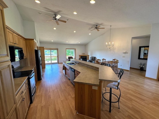 kitchen with light hardwood / wood-style floors, lofted ceiling, hanging light fixtures, black appliances, and a breakfast bar