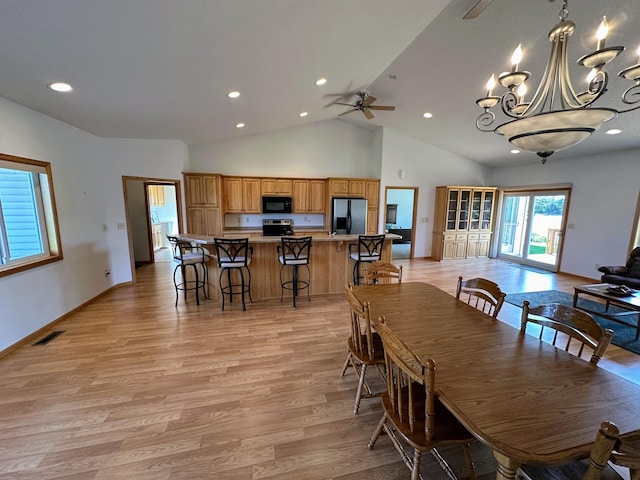 dining area featuring ceiling fan with notable chandelier, light hardwood / wood-style flooring, and vaulted ceiling