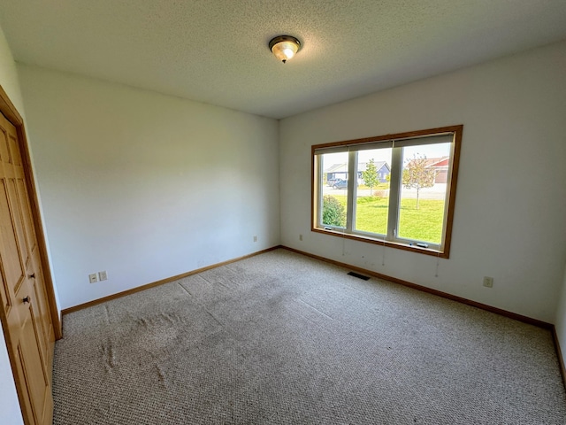 carpeted spare room featuring a textured ceiling