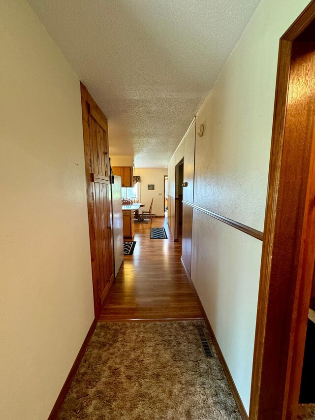 hallway featuring hardwood / wood-style floors and a textured ceiling