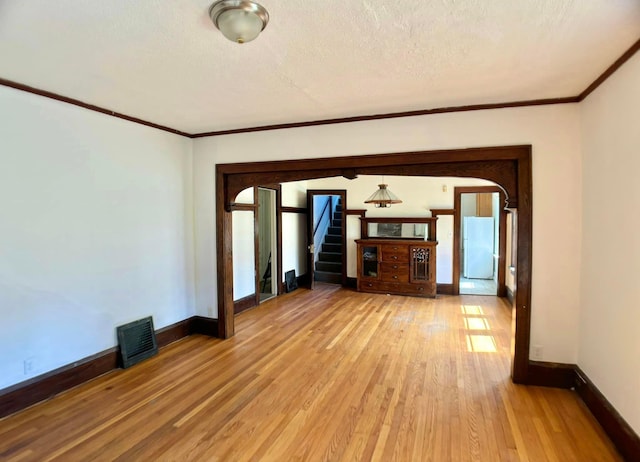 unfurnished room with ornamental molding, a textured ceiling, and hardwood / wood-style floors