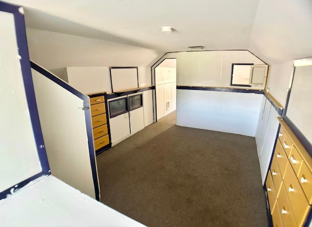 additional living space featuring dark colored carpet and vaulted ceiling