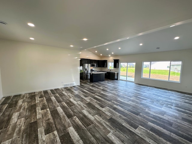 unfurnished living room with dark wood-type flooring, baseboards, lofted ceiling, and visible vents