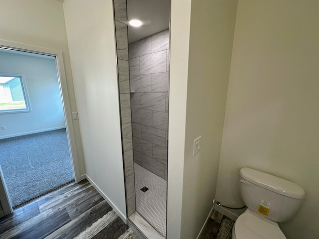 bathroom featuring tiled shower, toilet, and hardwood / wood-style flooring