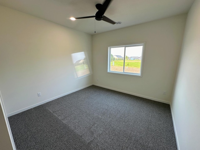 spare room with dark carpet, baseboards, and a ceiling fan