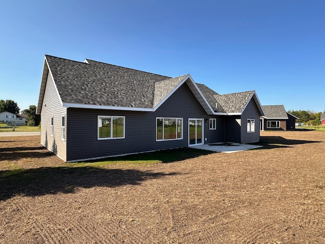 back of house with a patio area and roof with shingles