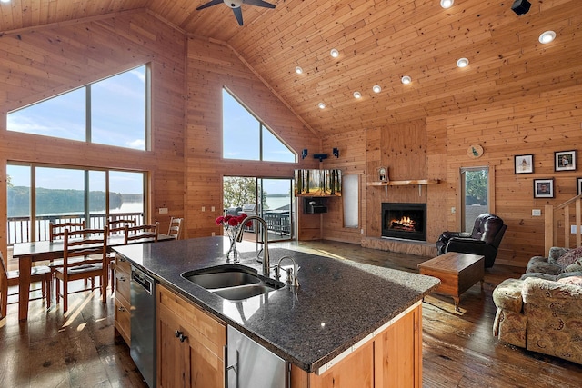 kitchen featuring dishwasher, a center island with sink, sink, a water view, and high vaulted ceiling