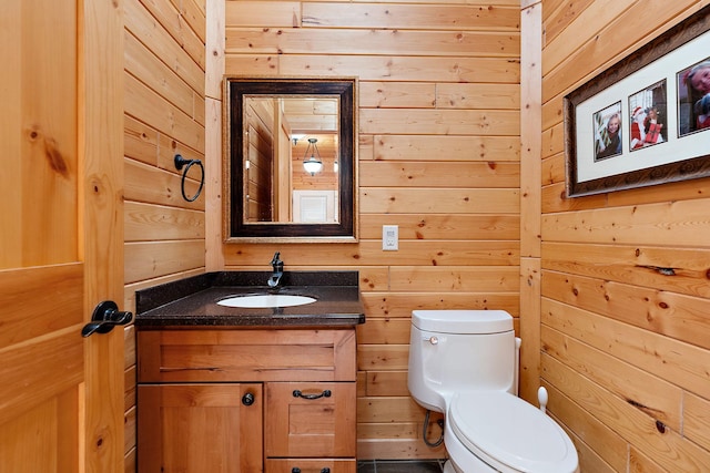 bathroom featuring vanity, toilet, and wooden walls