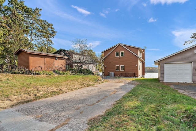 view of property exterior with central AC, a yard, a garage, and an outbuilding