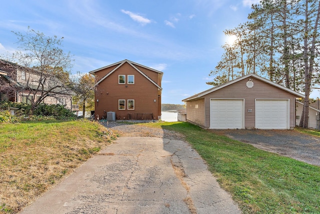 view of home's exterior with a garage, cooling unit, an outbuilding, and a lawn