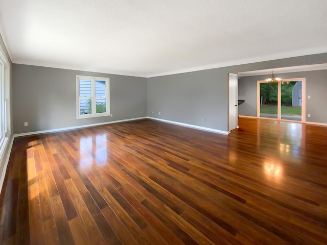 spare room featuring an inviting chandelier and dark hardwood / wood-style floors