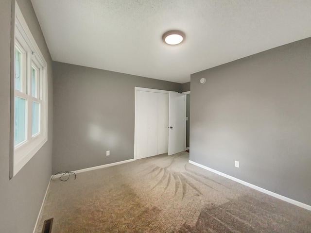 empty room with a textured ceiling and carpet floors