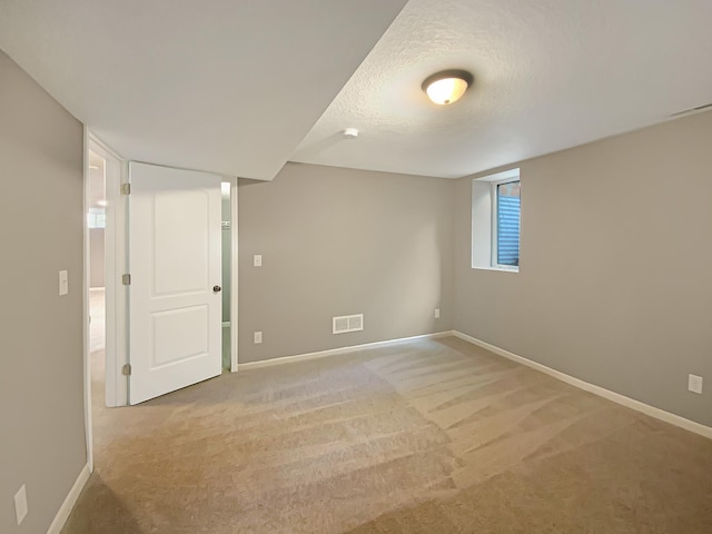 basement featuring a textured ceiling and light carpet