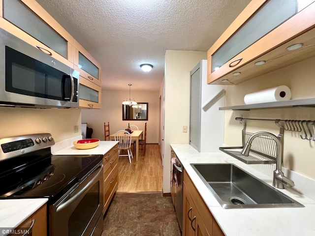 kitchen featuring an inviting chandelier, sink, a textured ceiling, appliances with stainless steel finishes, and decorative light fixtures