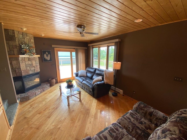 living room featuring a stone fireplace, wooden ceiling, a baseboard radiator, light wood-type flooring, and ceiling fan