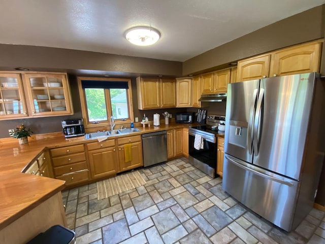 kitchen with sink, wooden counters, appliances with stainless steel finishes, and a textured ceiling