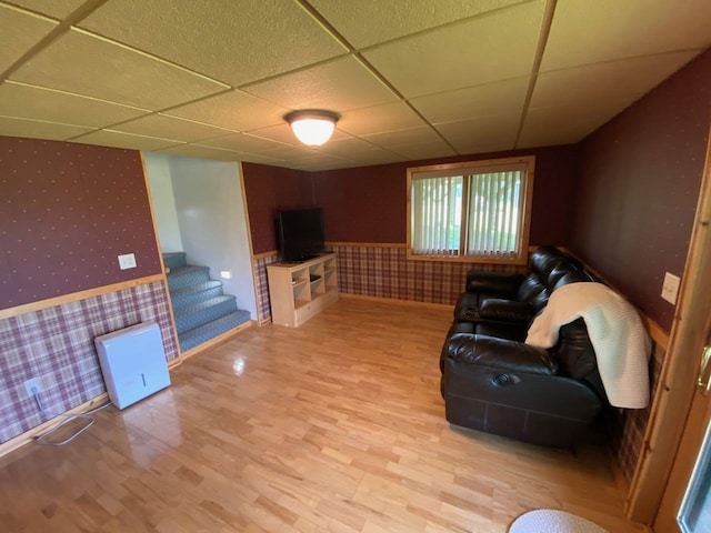 living room featuring light wood-type flooring and a drop ceiling