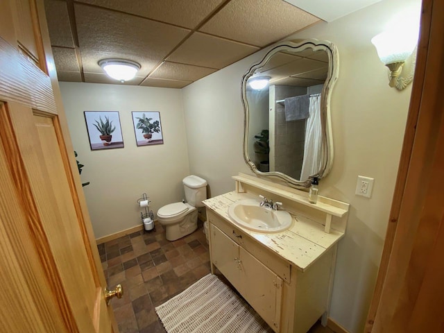 bathroom featuring toilet, a drop ceiling, and vanity