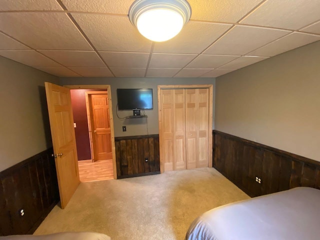 bedroom featuring a closet, carpet flooring, and wooden walls