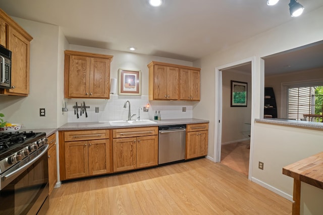 17661 Southridge Ct, Minnetonka, MN 55345 - kitchen with appliances with stainless steel finishes, a sink, light wood finished floors, light countertops, and backsplash