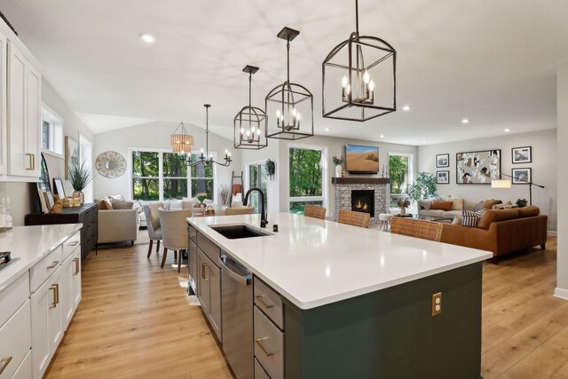 kitchen with plenty of natural light, decorative light fixtures, sink, and a kitchen island with sink