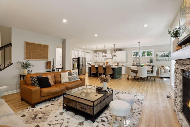 living room featuring light wood-type flooring, a fireplace, and a chandelier