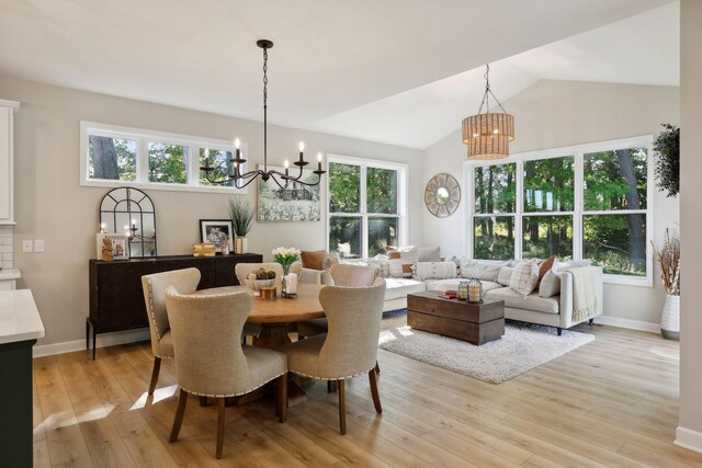 dining area with lofted ceiling, light wood-type flooring, an inviting chandelier, and a wealth of natural light