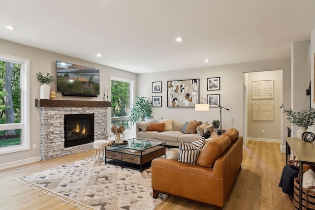 living room featuring light wood-type flooring, a fireplace, and a wealth of natural light