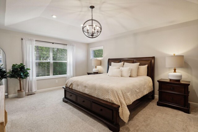 carpeted bedroom featuring a tray ceiling and a chandelier