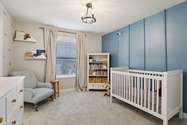 bedroom featuring light carpet, a crib, and a textured ceiling