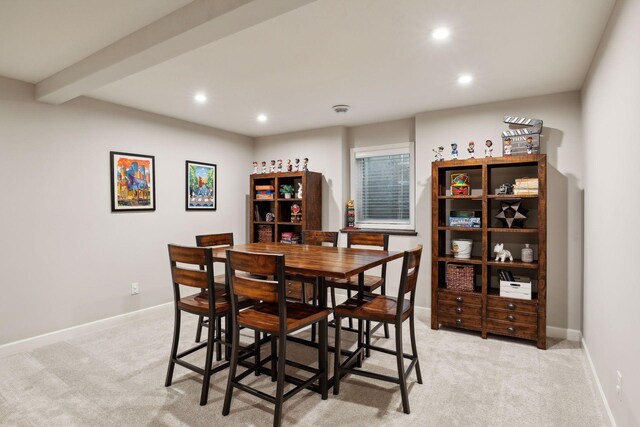 dining room featuring light carpet and beamed ceiling