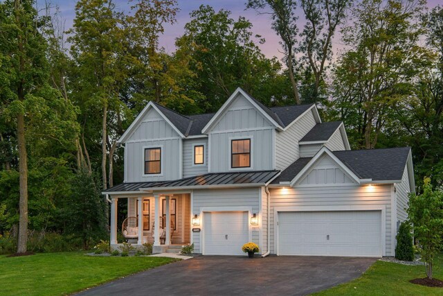 view of front of home featuring aphalt driveway, a lawn, board and batten siding, and roof with shingles