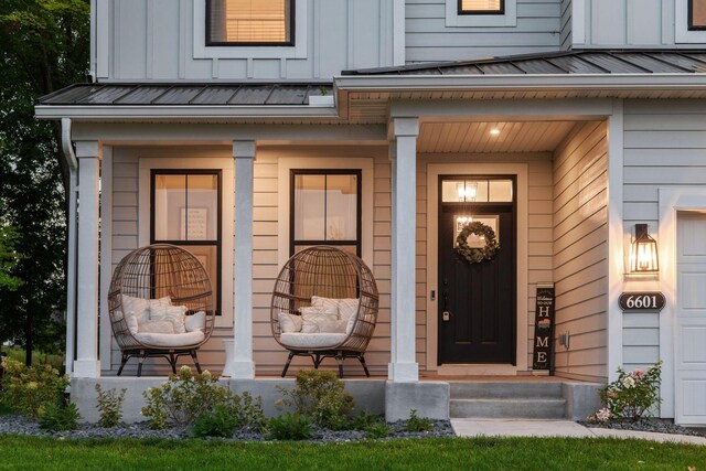 doorway to property with a standing seam roof, covered porch, board and batten siding, and metal roof