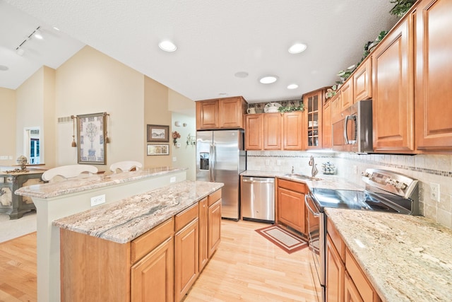 kitchen featuring appliances with stainless steel finishes, a kitchen breakfast bar, light wood-type flooring, and tasteful backsplash