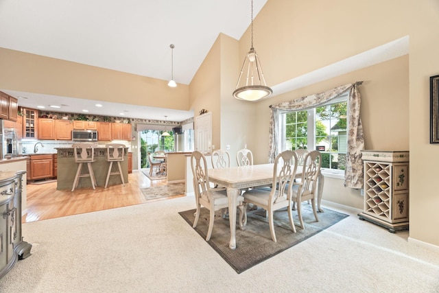 dining space featuring light carpet, baseboards, high vaulted ceiling, and a wealth of natural light