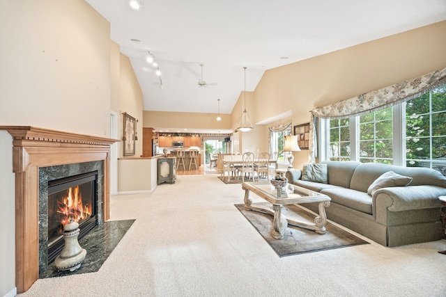 carpeted living room featuring high vaulted ceiling, a premium fireplace, a wealth of natural light, and track lighting