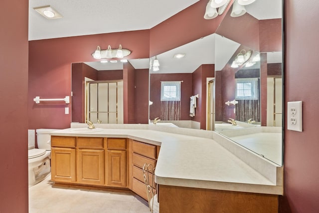 bathroom featuring toilet, a shower with shower door, tile patterned floors, and vanity