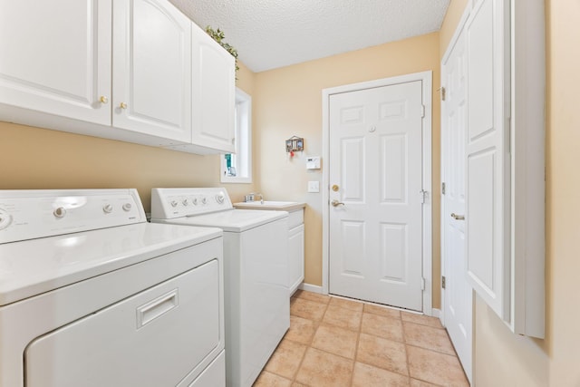 washroom with cabinet space, washing machine and clothes dryer, a textured ceiling, a sink, and light tile patterned flooring