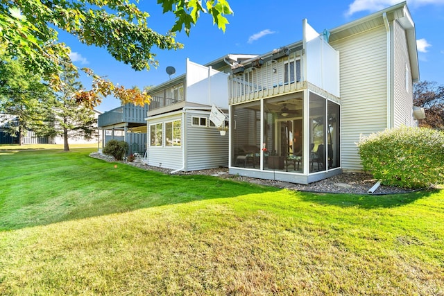 rear view of property featuring a balcony, a sunroom, and a yard