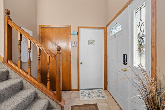 tiled foyer featuring baseboards, a high ceiling, and stairway