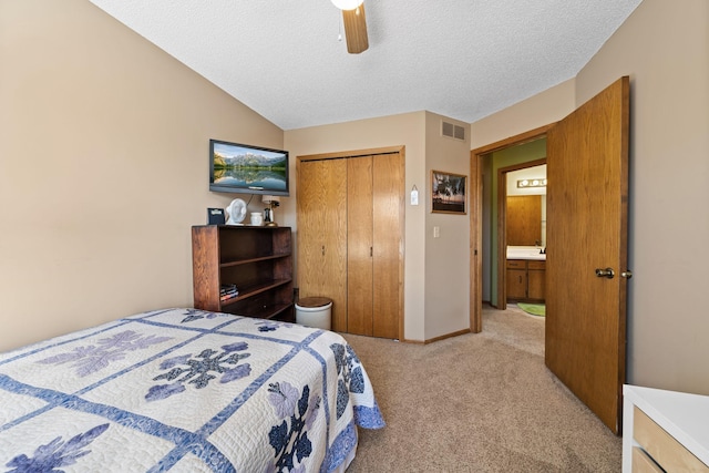 bedroom with a closet, a textured ceiling, visible vents, vaulted ceiling, and light colored carpet