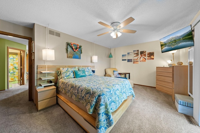 bedroom featuring light carpet, visible vents, ceiling fan, and a textured ceiling