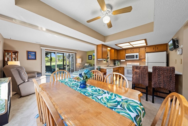 dining room with light colored carpet, ceiling fan, and a textured ceiling