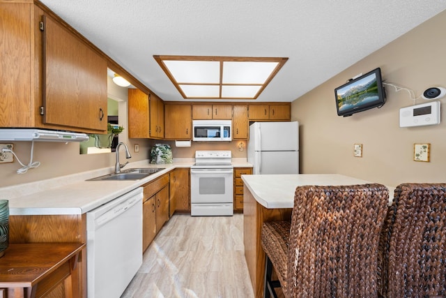 kitchen with light countertops, a sink, brown cabinets, and white appliances