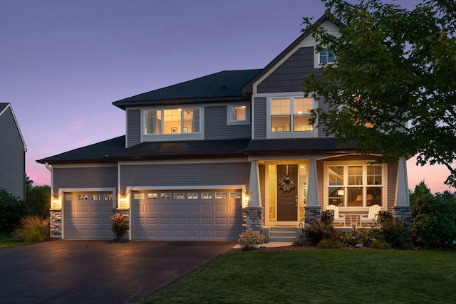craftsman-style house with a front yard, driveway, an attached garage, stone siding, and covered porch