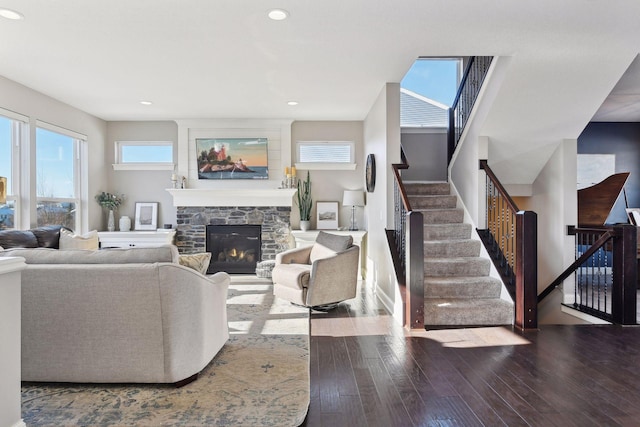 living room with hardwood / wood-style floors, a stone fireplace, stairs, and recessed lighting