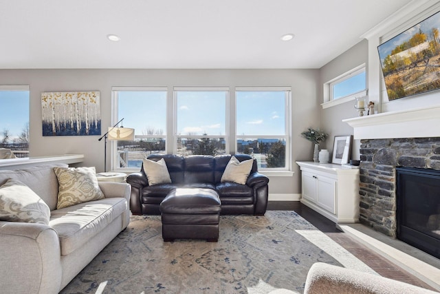 living area with a stone fireplace, wood finished floors, baseboards, and recessed lighting