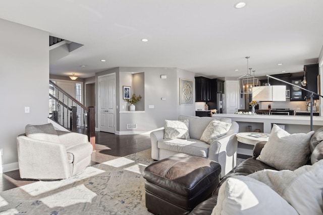 living room with baseboards, wood finished floors, stairs, recessed lighting, and a chandelier